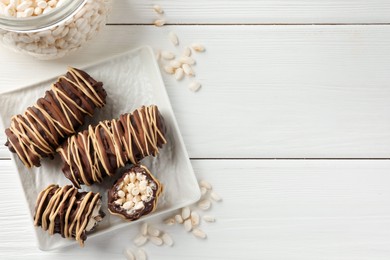 Photo of Delicious chocolate puffed rice bars on white wooden table, flat lay. Space for text