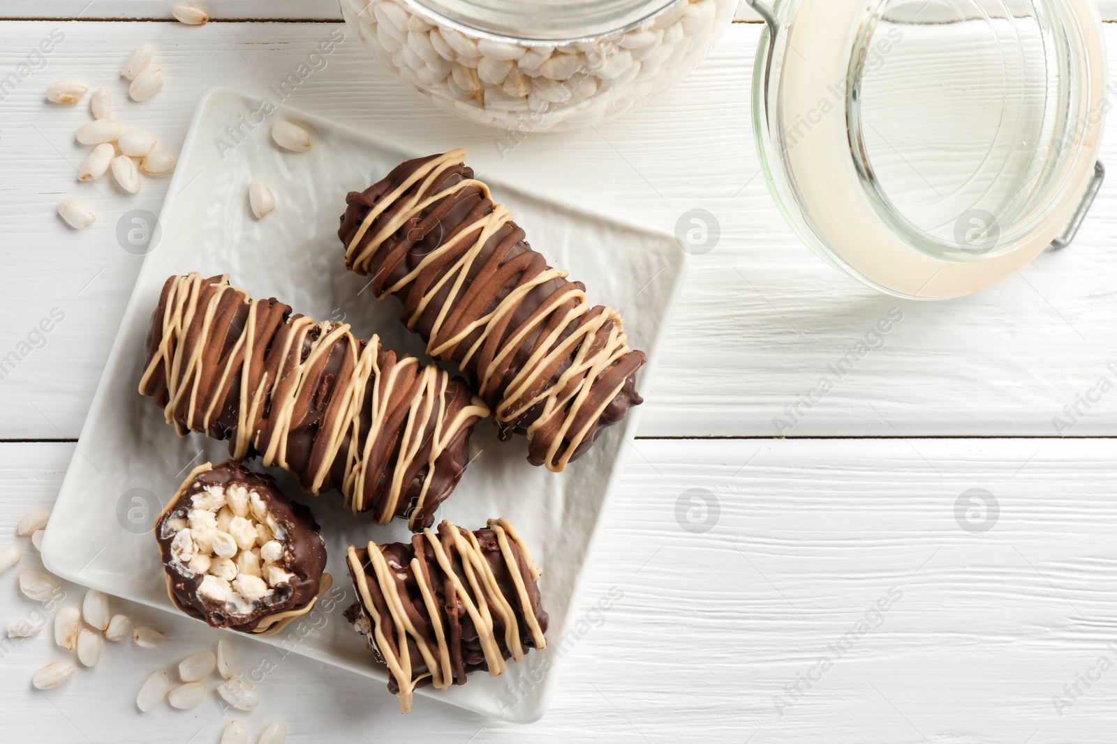 Photo of Delicious chocolate puffed rice bars on white wooden table, flat lay. Space for text