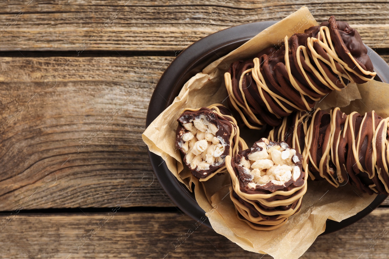 Photo of Delicious chocolate puffed rice bars on wooden table, top view. Space for text