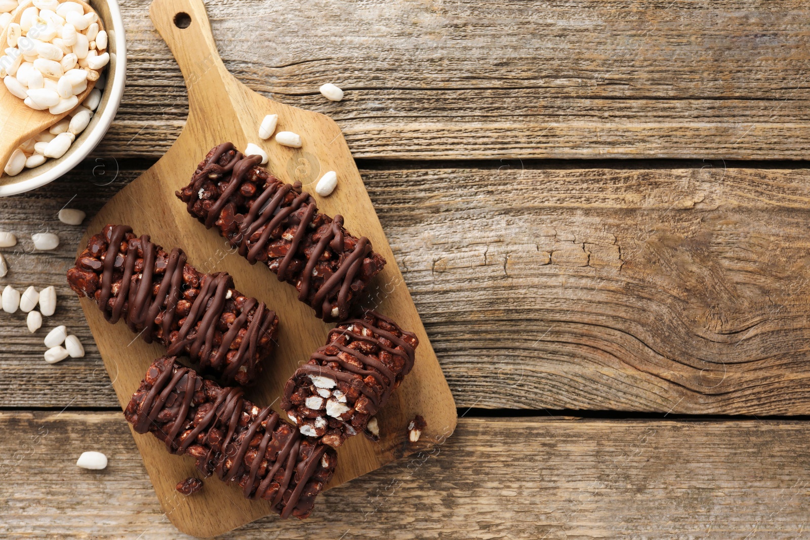 Photo of Delicious chocolate puffed rice bars on wooden table, flat lay. Space for text