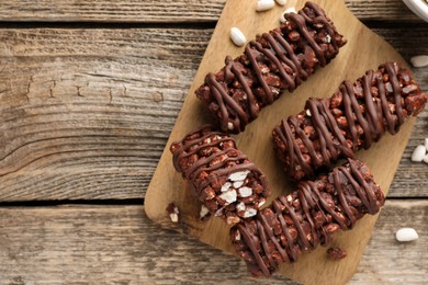 Photo of Delicious chocolate puffed rice bars on wooden table, flat lay. Space for text