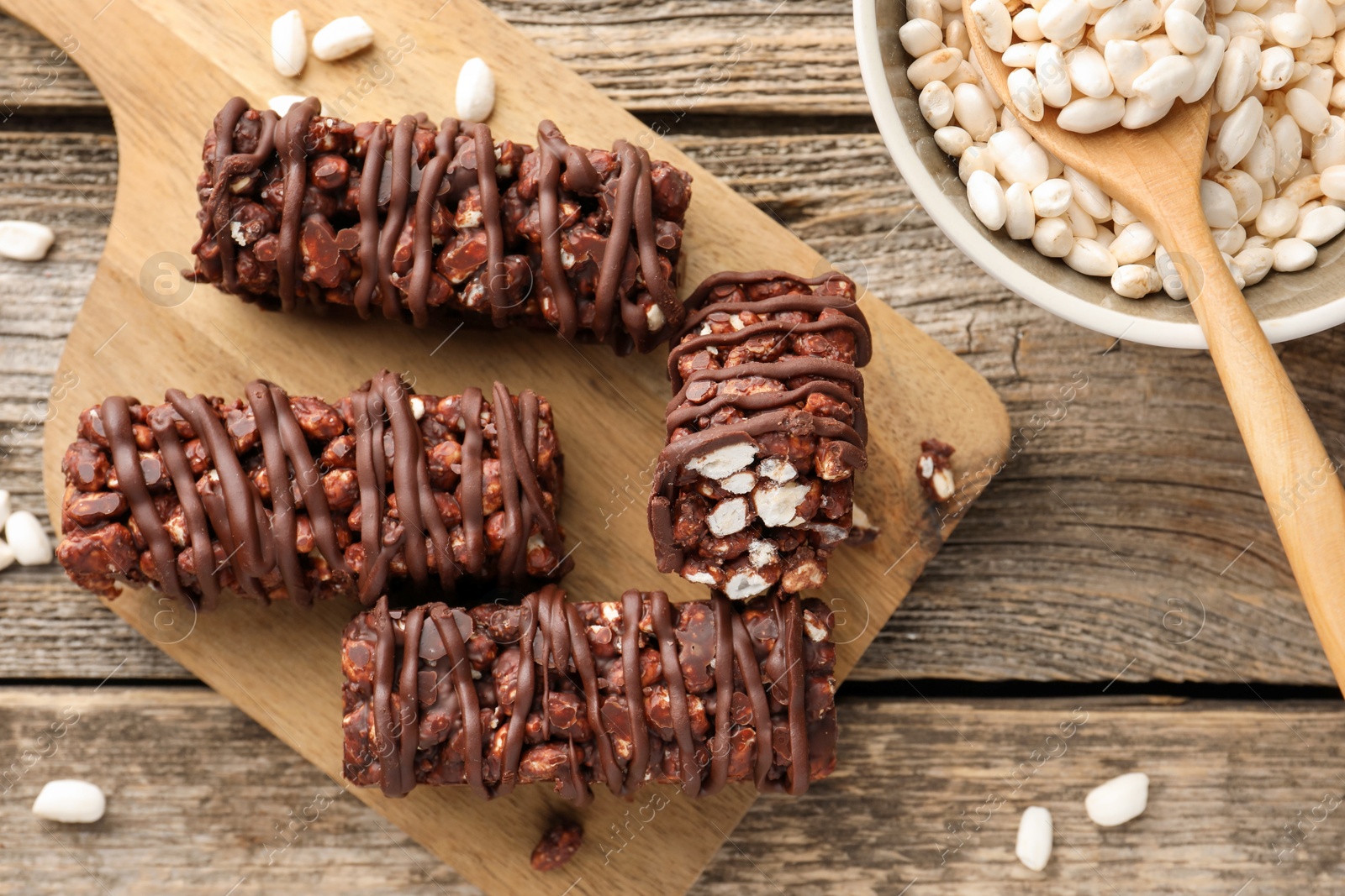 Photo of Delicious chocolate puffed rice bars on wooden table, flat lay