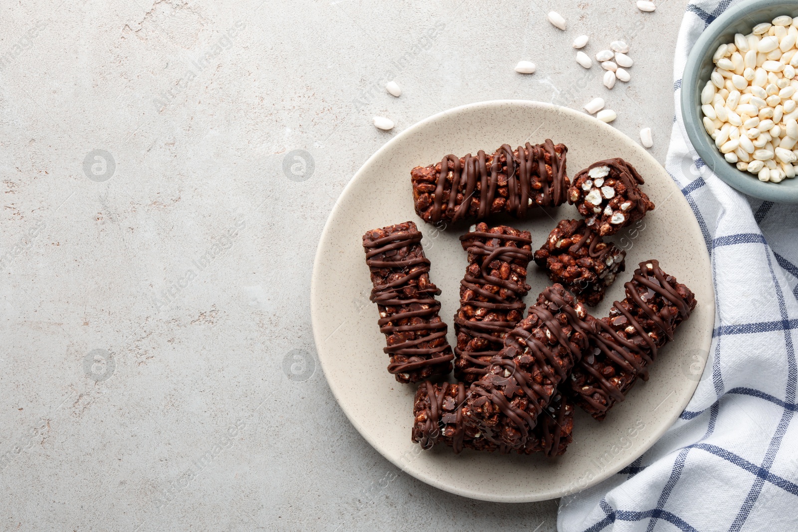 Photo of Delicious chocolate puffed rice bars on gray textured table, flat lay. Space for text