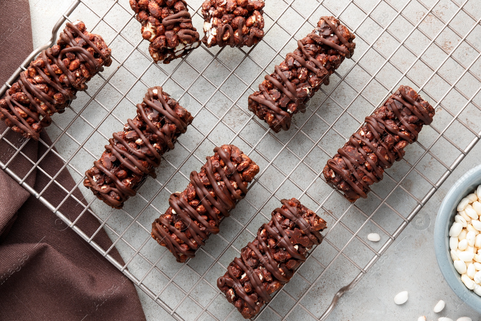 Photo of Delicious chocolate puffed rice bars on gray textured table, flat lay