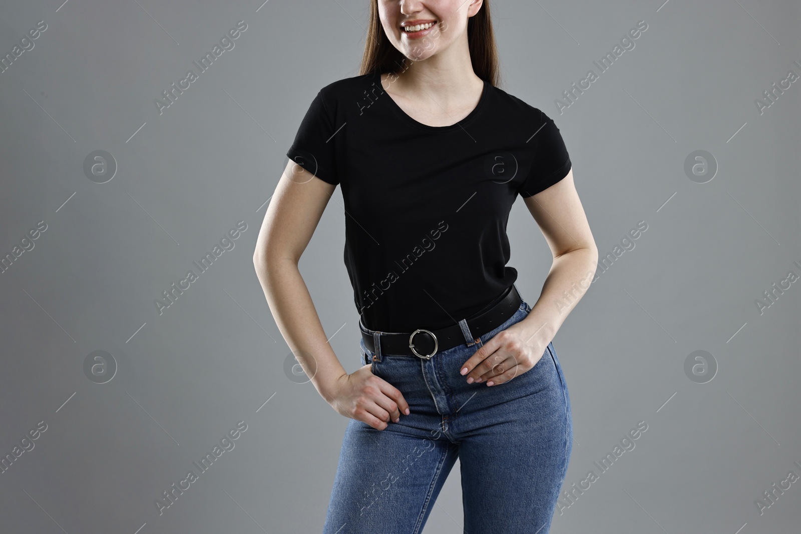 Photo of Smiling woman in stylish jeans on grey background, closeup