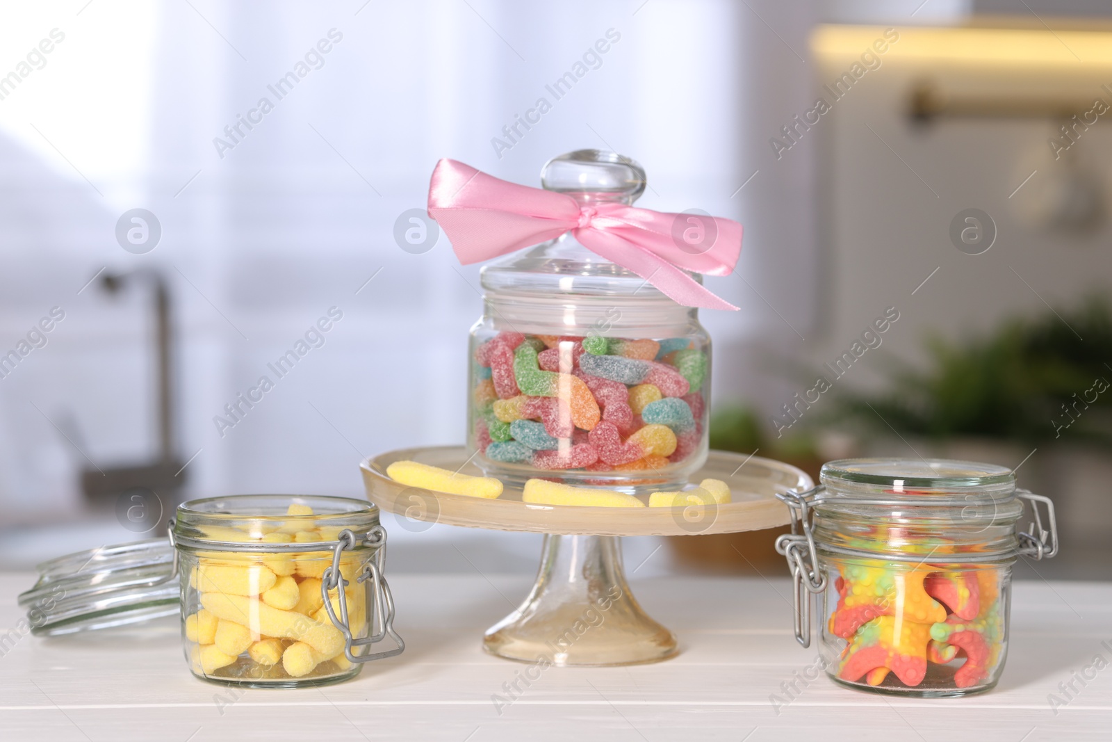 Photo of Tasty gummy candies in jars on light wooden table indoors