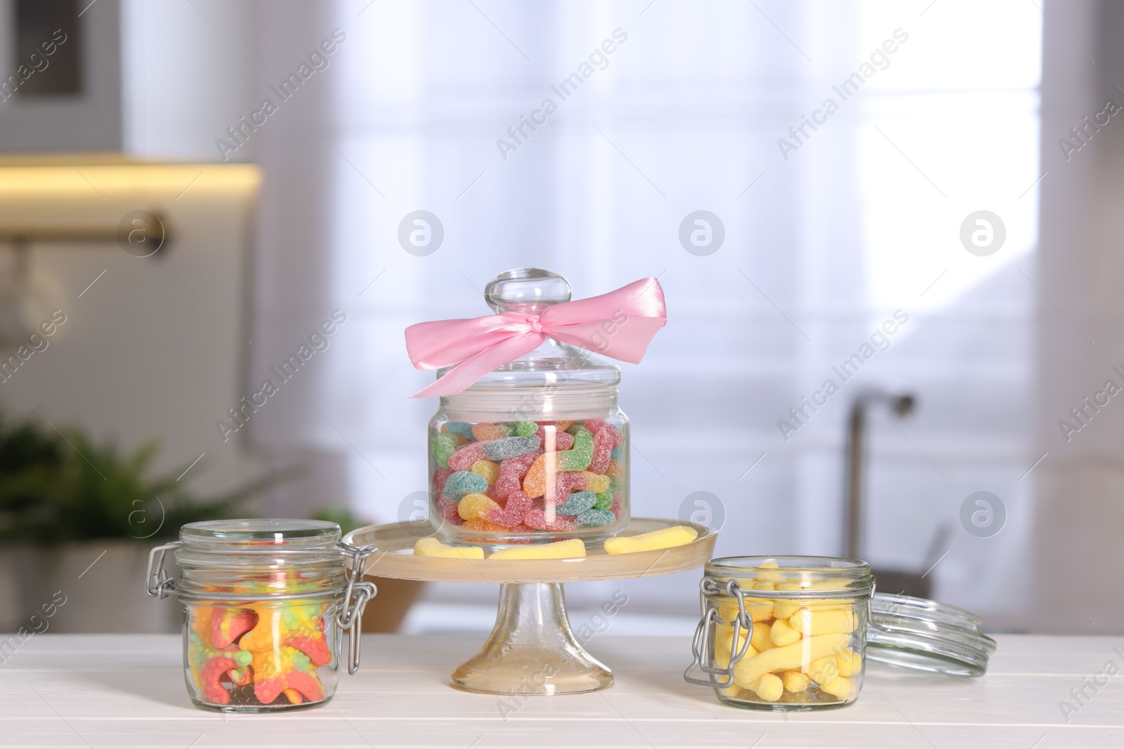 Photo of Tasty gummy candies in jars on light wooden table indoors