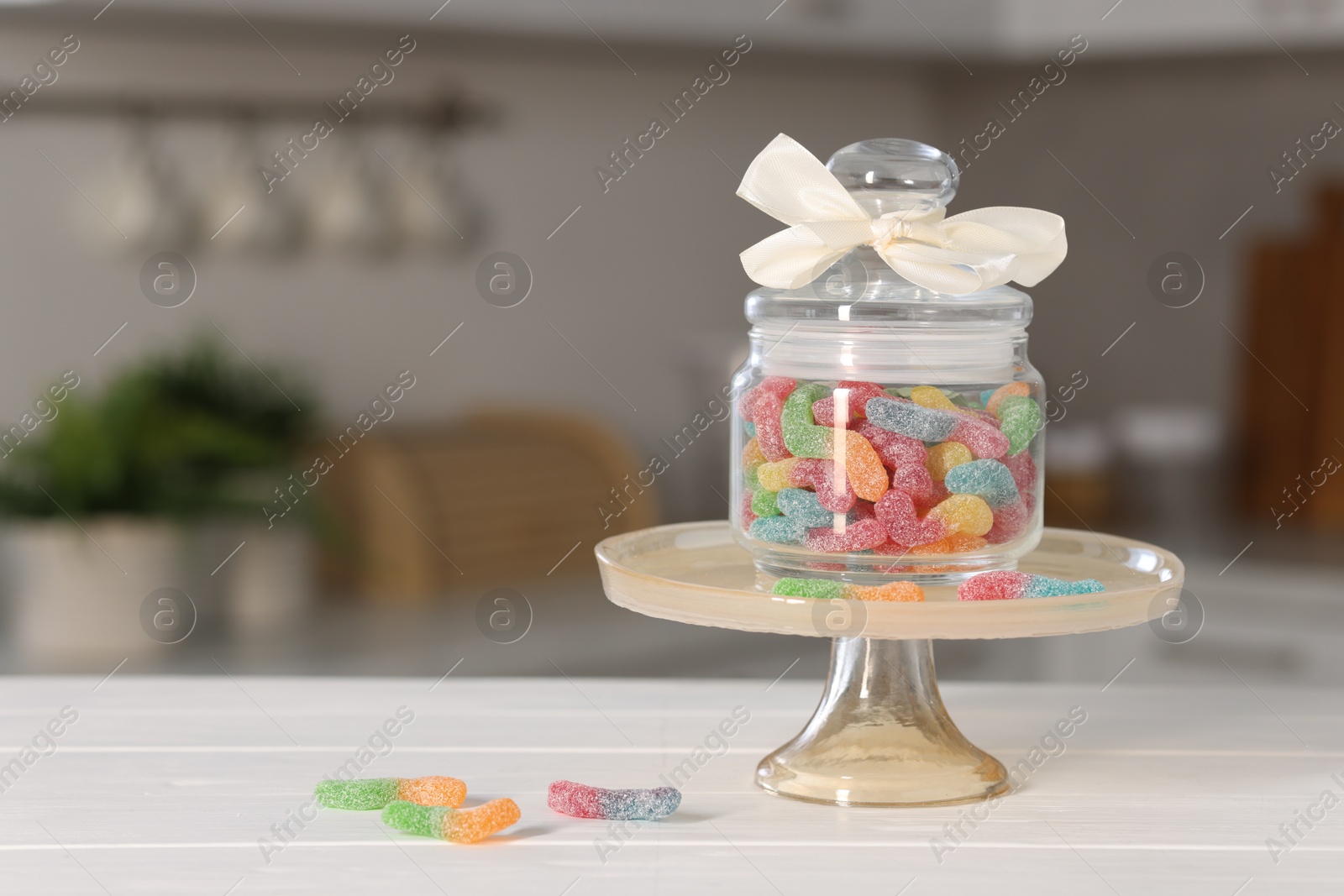 Photo of Tasty gummy candies in jar on light wooden table indoors, space for text