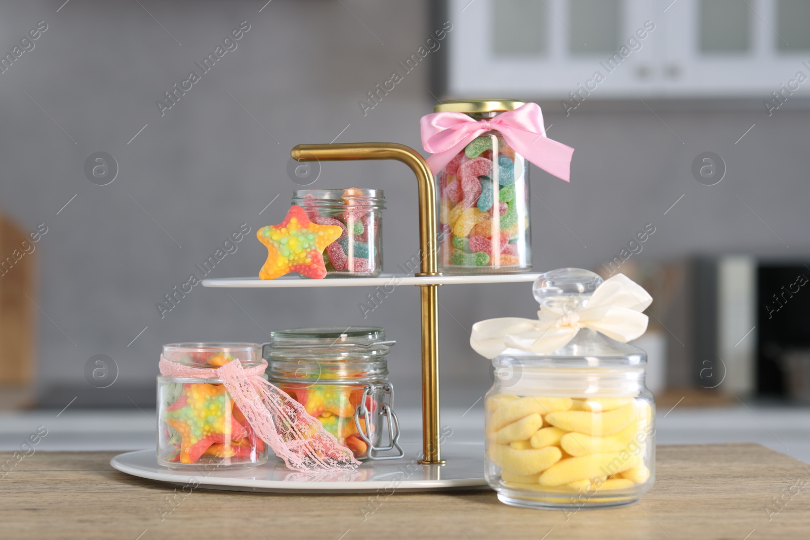 Photo of Tasty gummy candies in jars on wooden table indoors