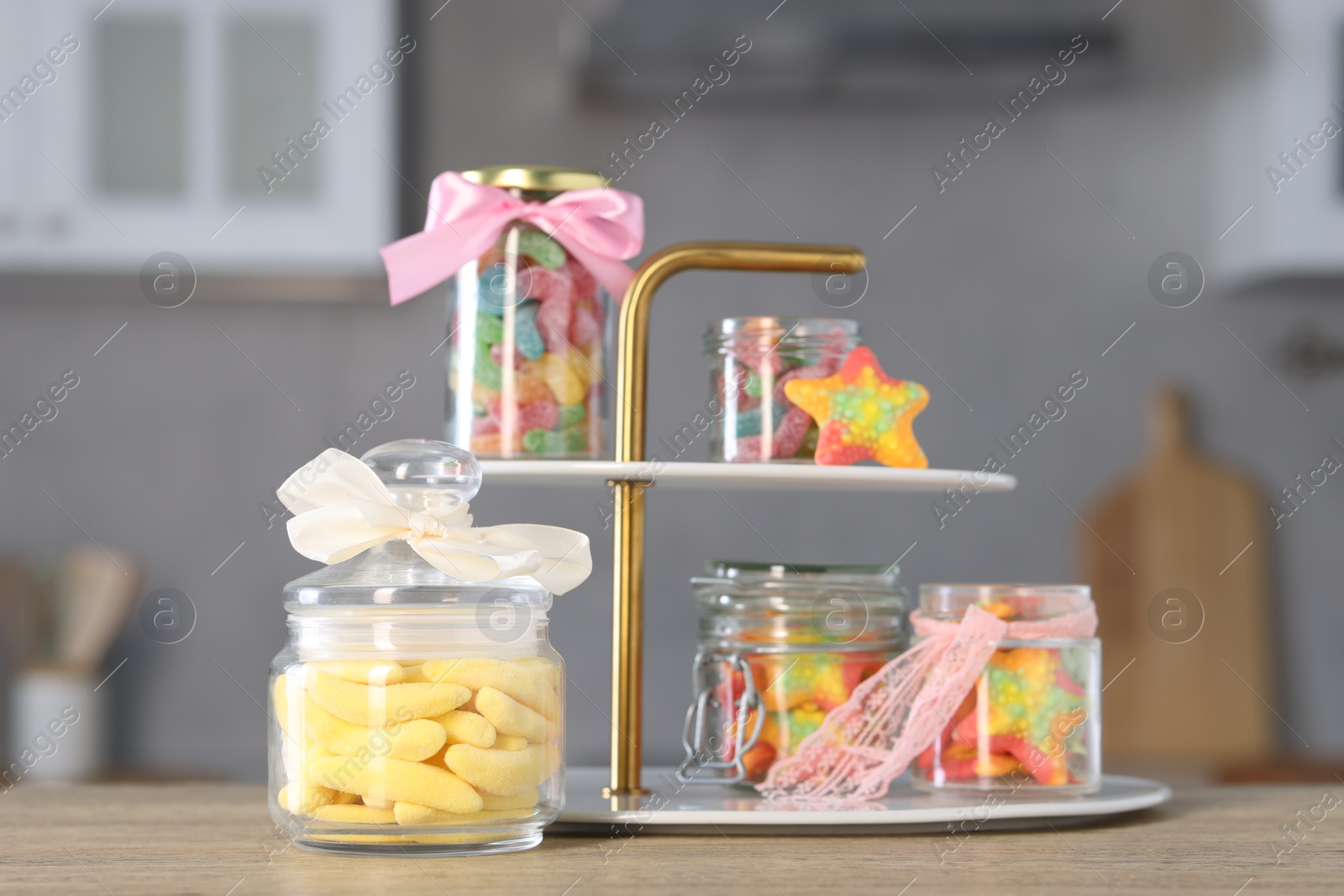 Photo of Tasty gummy candies in jars on wooden table indoors