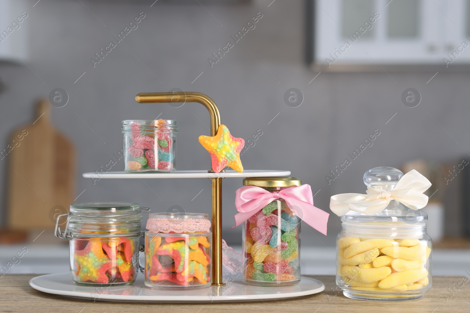 Photo of Tasty gummy candies in jars on wooden table indoors