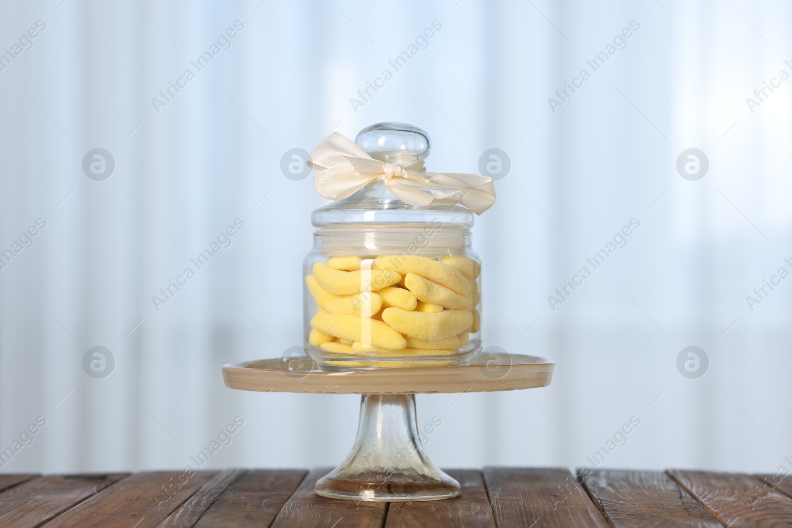 Photo of Tasty gummy candies in jar on wooden table indoors