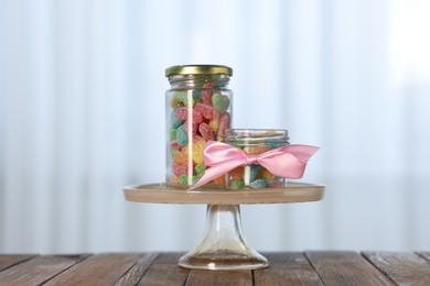 Photo of Tasty gummy candies in jars on wooden table indoors