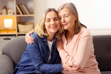 Photo of Smiling mother and her daughter on sofa at home