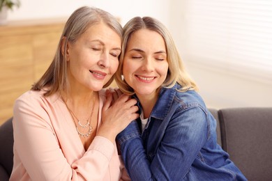 Photo of Smiling mother and her daughter on sofa at home