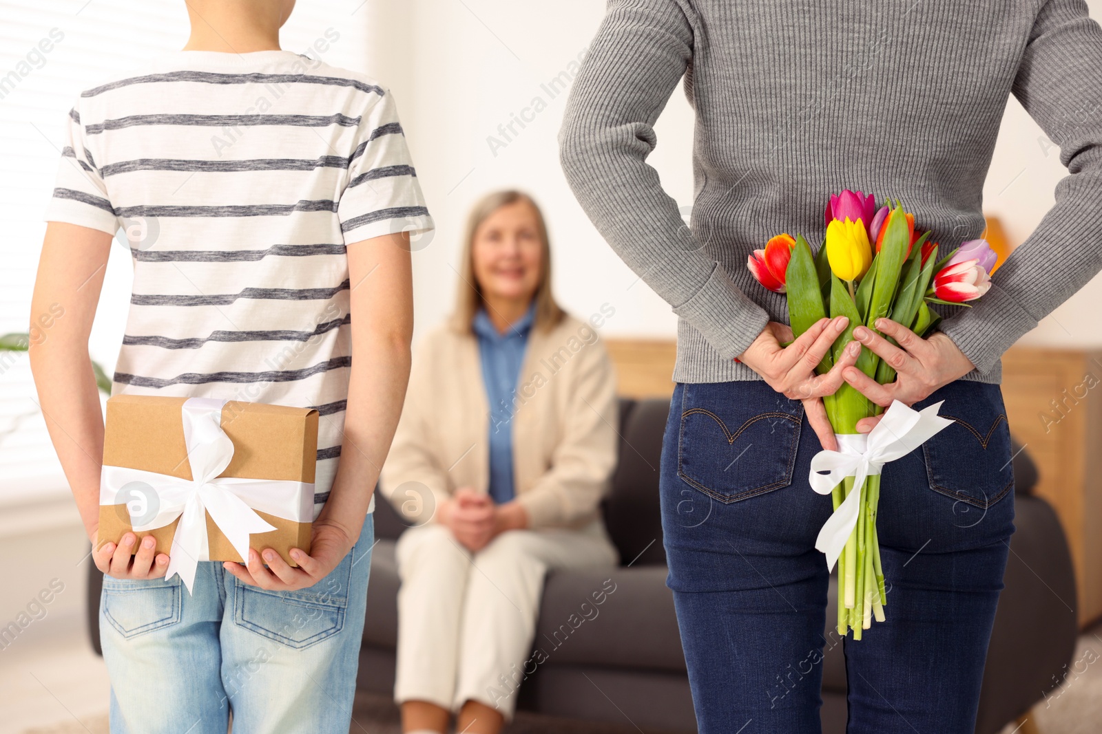 Photo of Mother and son hiding gifts behind backs for their parent at home, selective focus. Happy Mother's Day