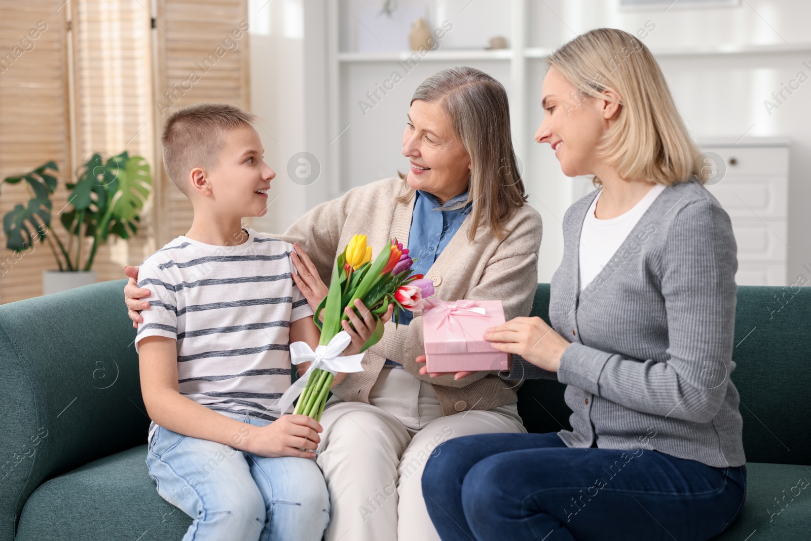 Photo of Mother and son congratulating their happy parent with Mother's Day on sofa at home