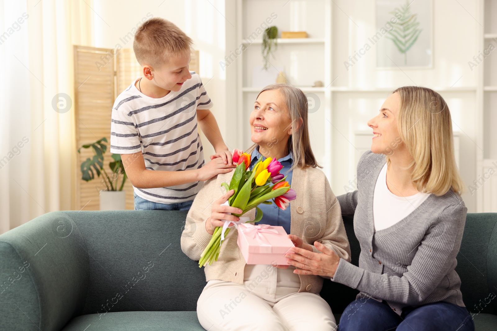 Photo of Mother and son congratulating their happy parent with Mother's Day on sofa at home