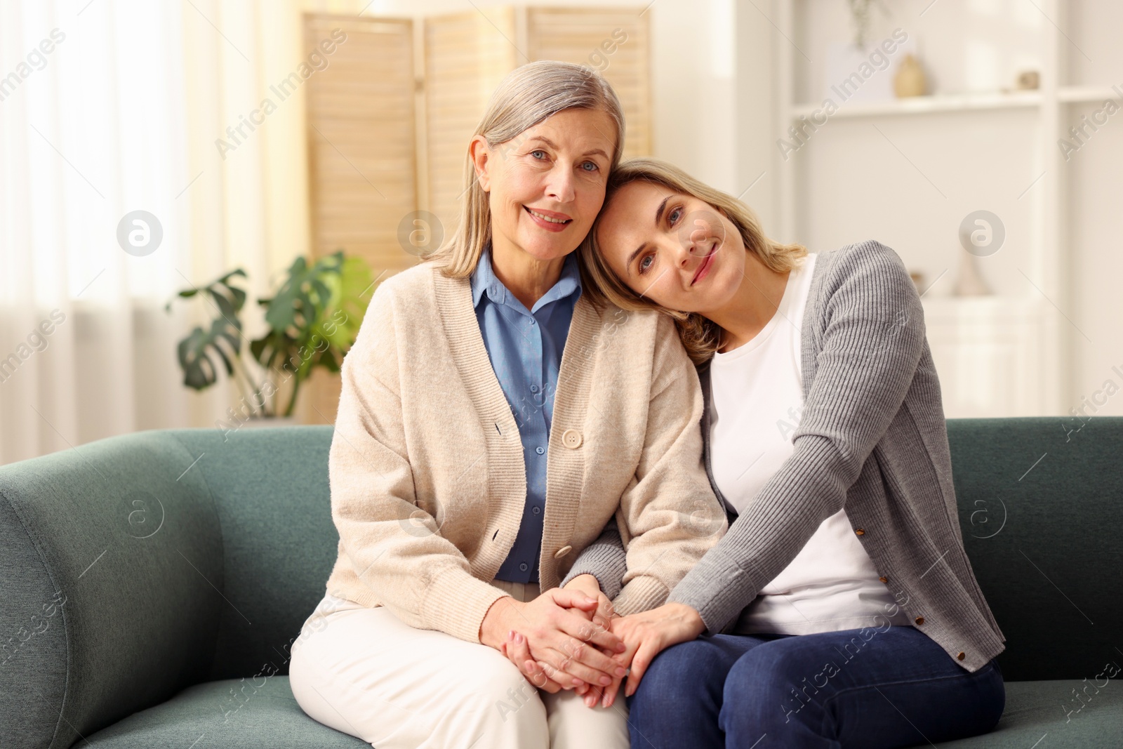 Photo of Family portrait of smiling mother and her daughter on sofa at home