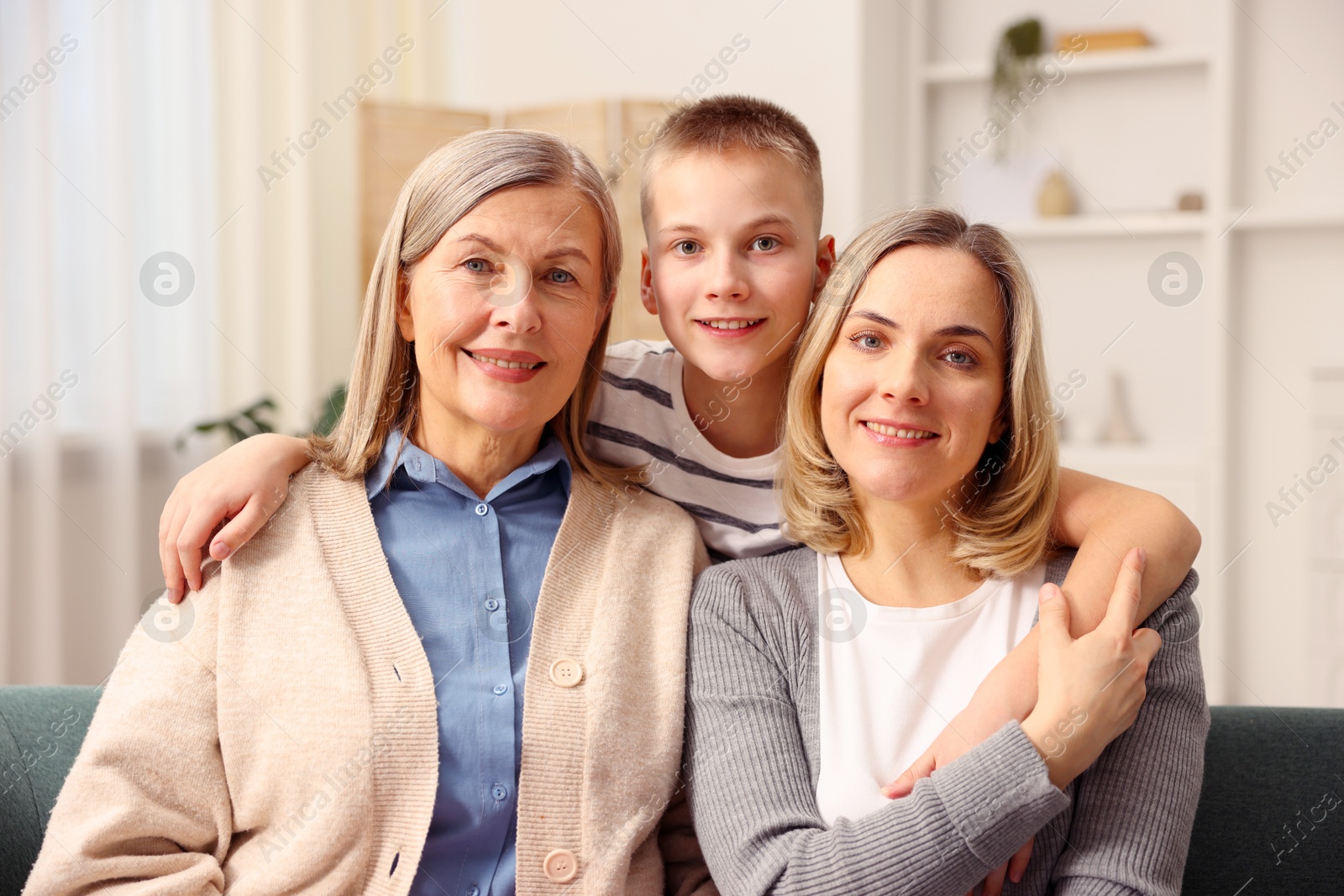 Photo of Family portrait of smiling woman, her mother and son at home