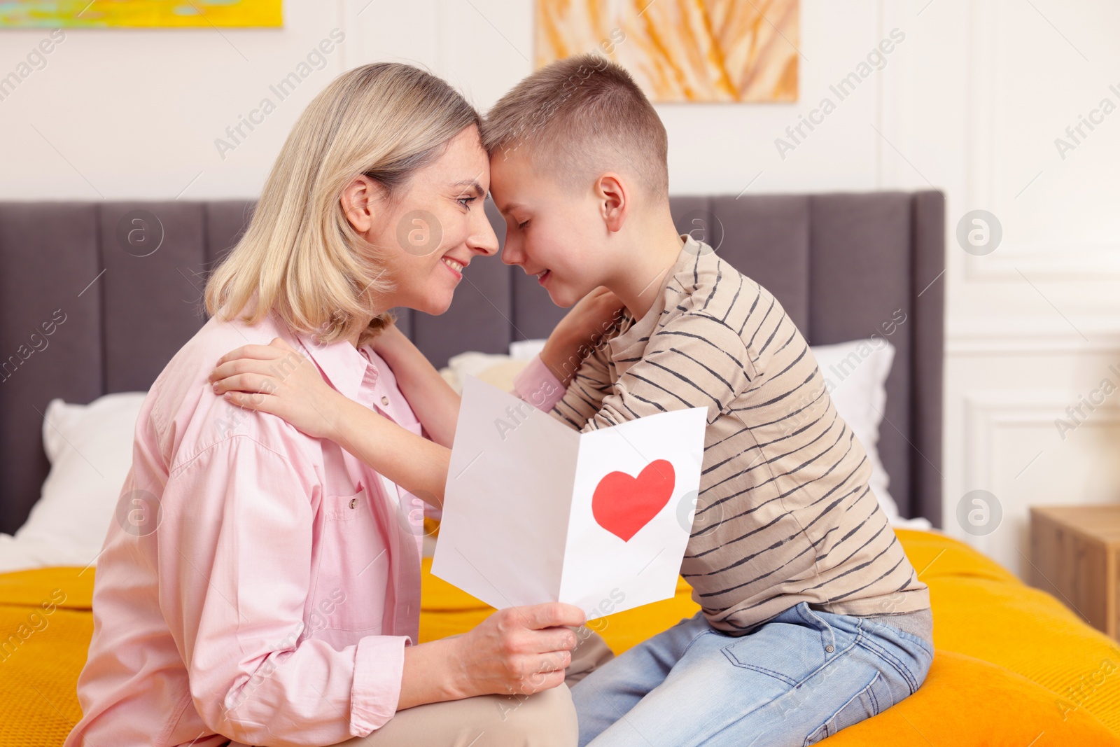 Photo of Happy Mother's Day. Son greeting his mom with card on bed indoors