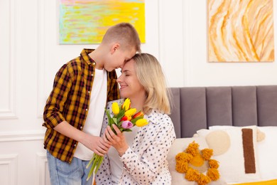 Photo of Happy Mother's Day. Son surprising his mom with flowers at home