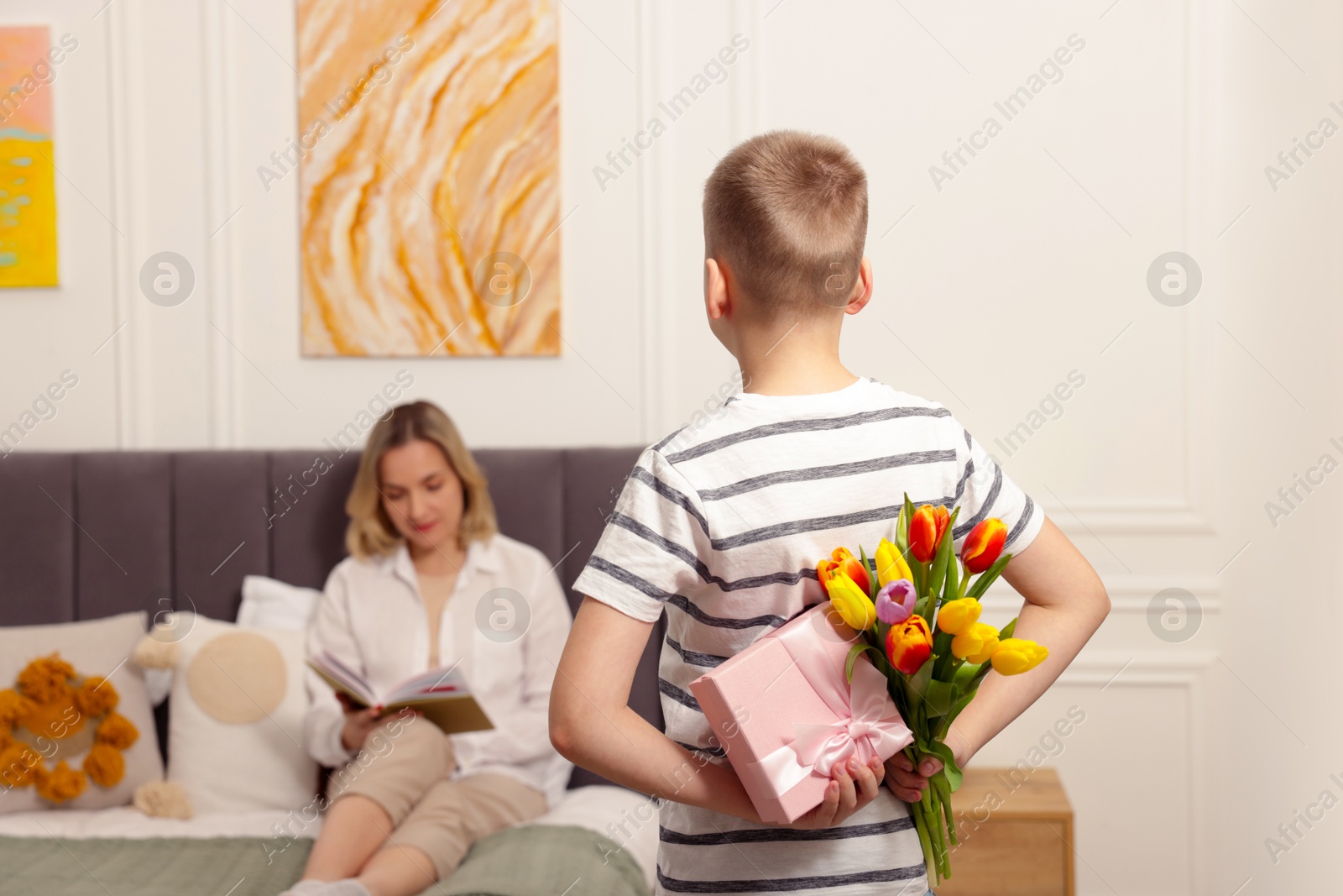 Photo of Happy Mother's Day. Son surprising his mom with gift and flowers at home, selective focus