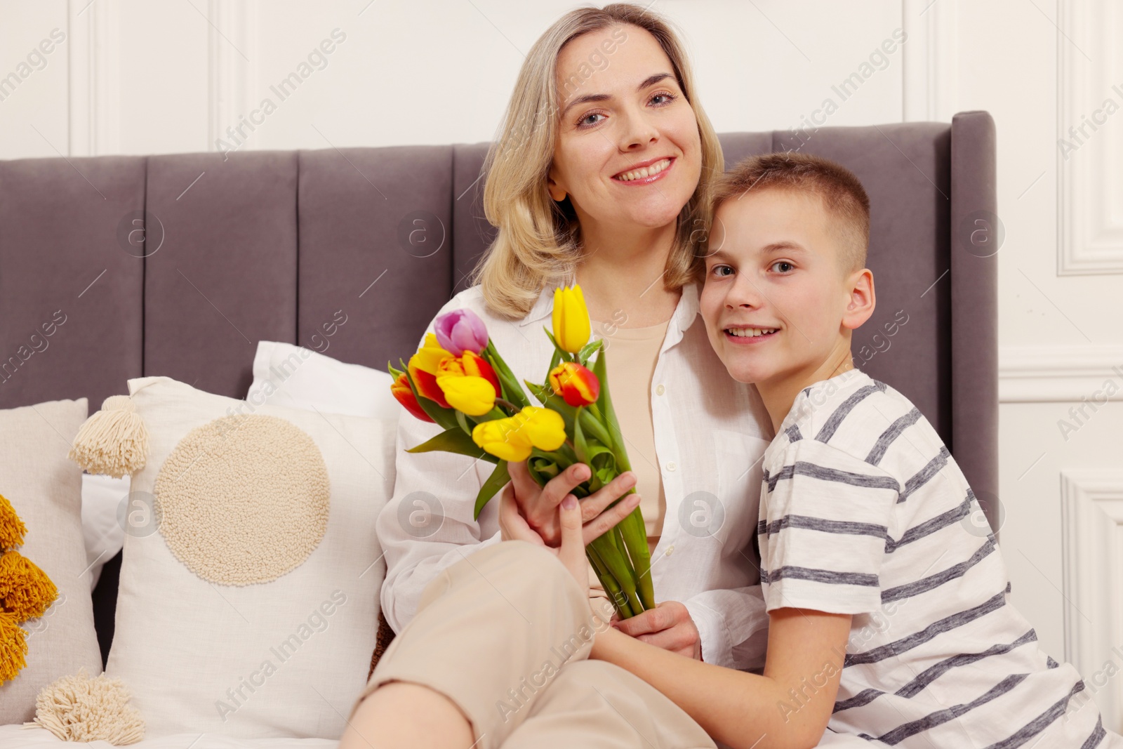 Photo of Happy Mother's Day. Son greeting his mom with flowers at home