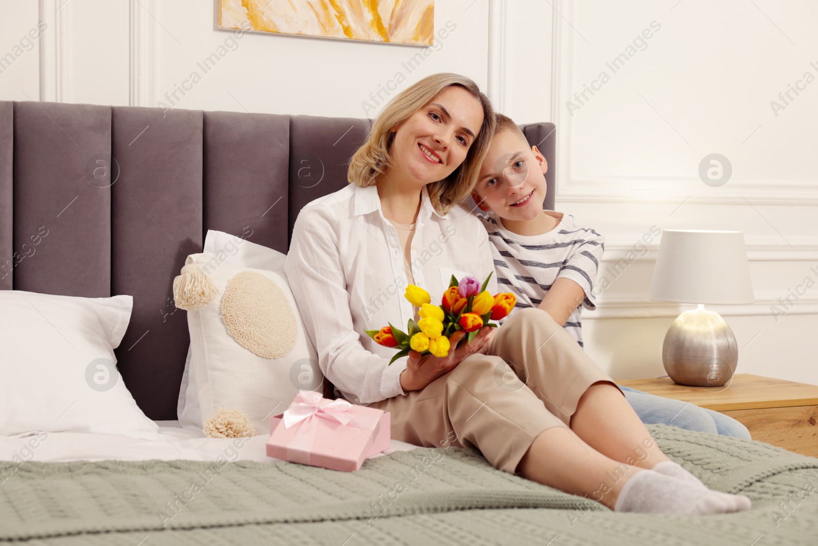 Photo of Happy Mother's Day. Son greeting his mom with flowers and gift at home