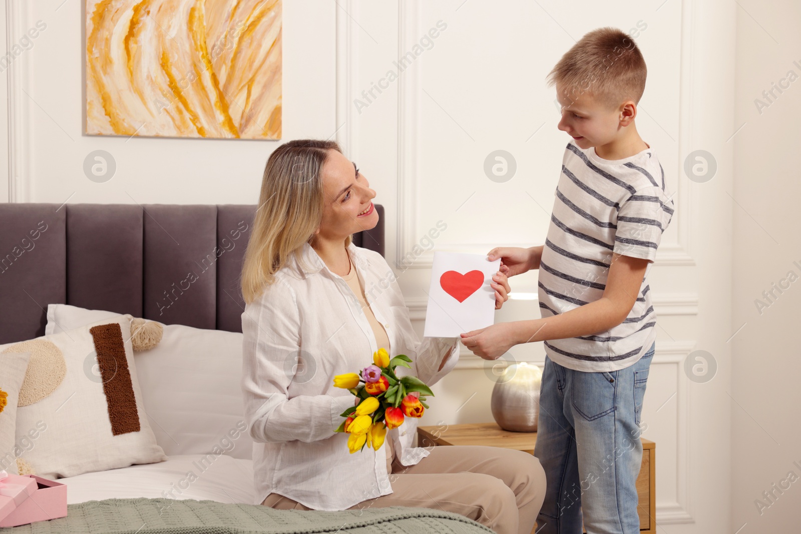 Photo of Happy Mother's Day. Son greeting his mom with flowers and card at home