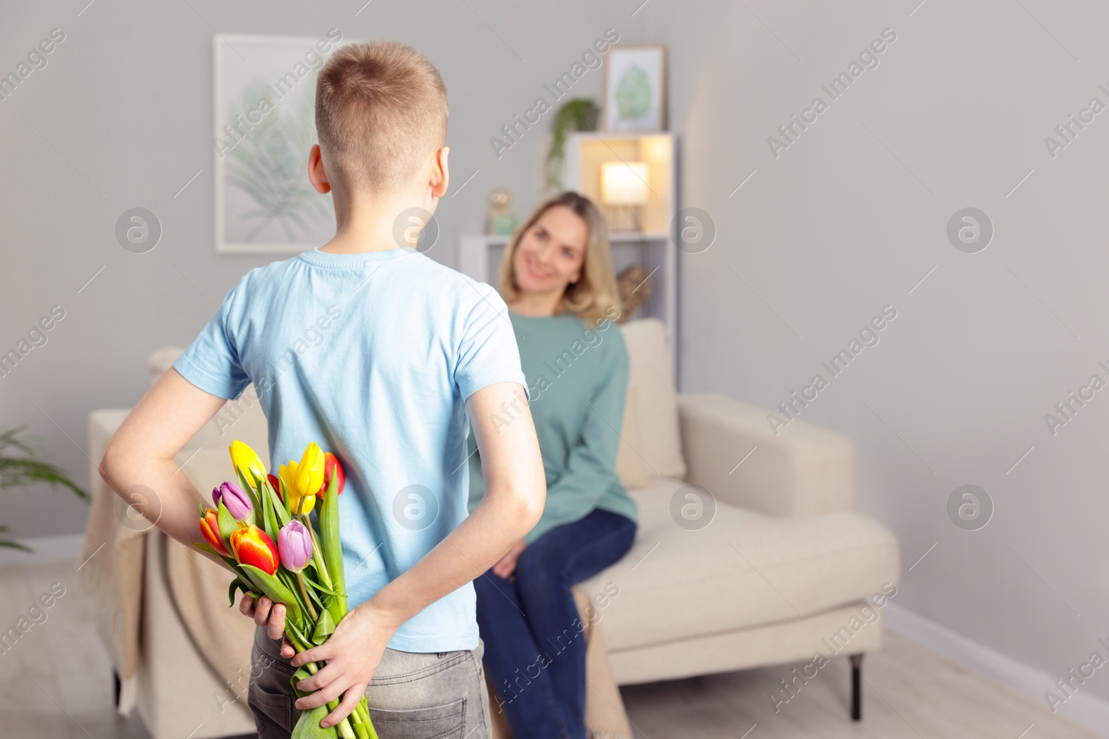 Photo of Happy Mother's Day. Son surprising his mom with flowers at home, selective focus