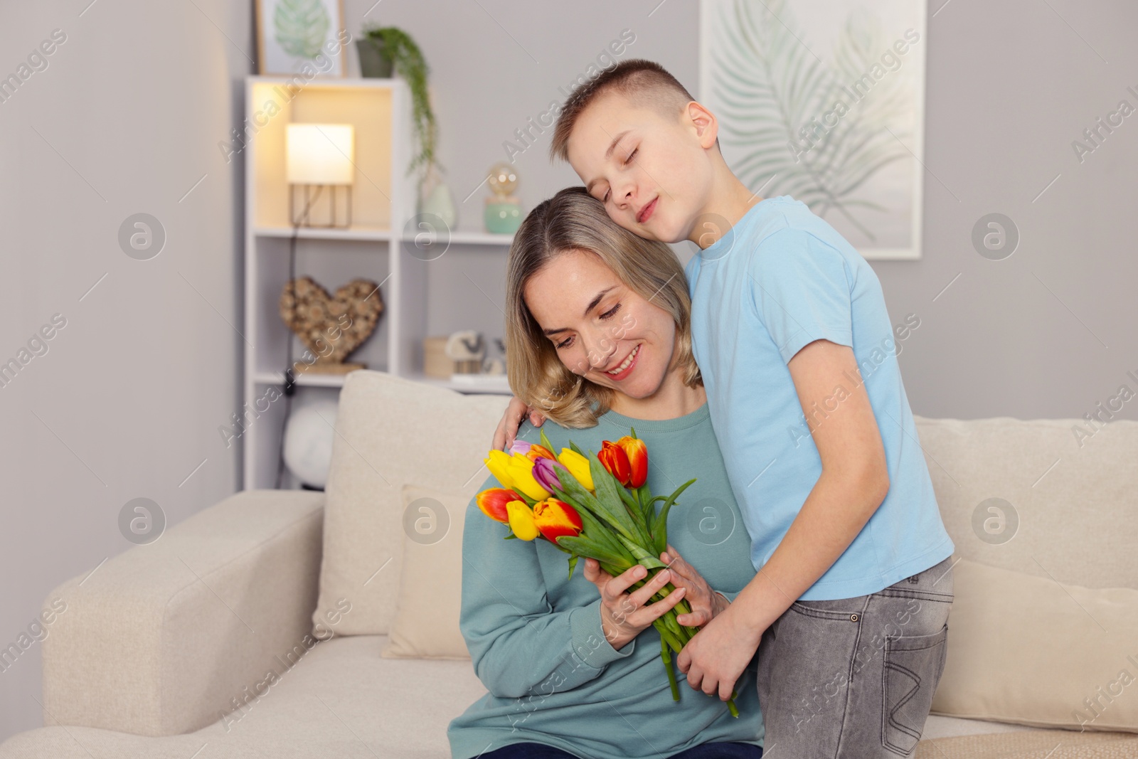 Photo of Happy Mother's Day. Son greeting his mom with flowers at home. Space for text