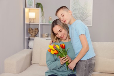 Photo of Happy Mother's Day. Son greeting his mom with flowers at home. Space for text