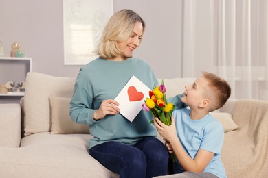 Photo of Happy Mother's Day. Son greeting his mom with flowers and card at home