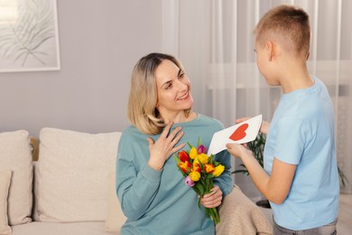 Photo of Happy Mother's Day. Son greeting his mom with flowers and card at home