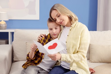 Photo of Happy Mother's Day. Son greeting his mom with card at home