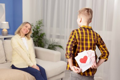 Photo of Happy Mother's Day. Son surprising his mom with gift and card at home, selective focus