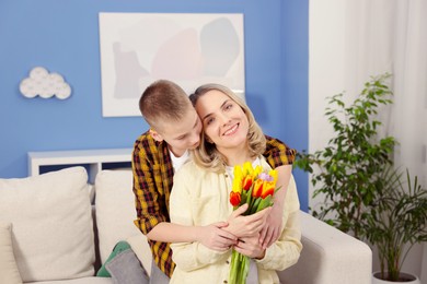 Photo of Happy Mother's Day. Son greeting his mom with flowers at home