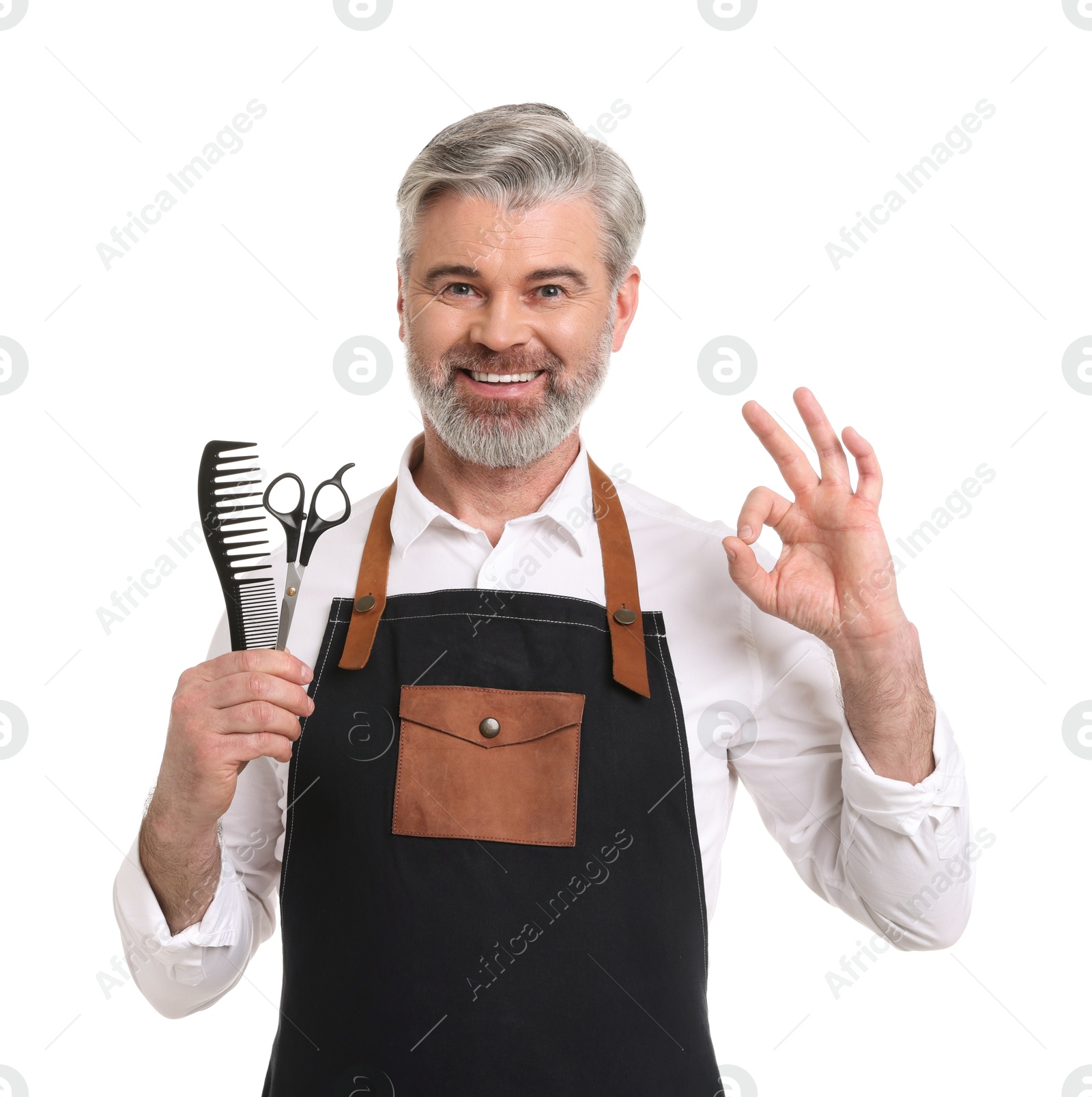 Photo of Smiling hairdresser with comb and scissors showing OK gesture on white background