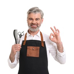 Photo of Smiling hairdresser with comb and scissors showing OK gesture on white background