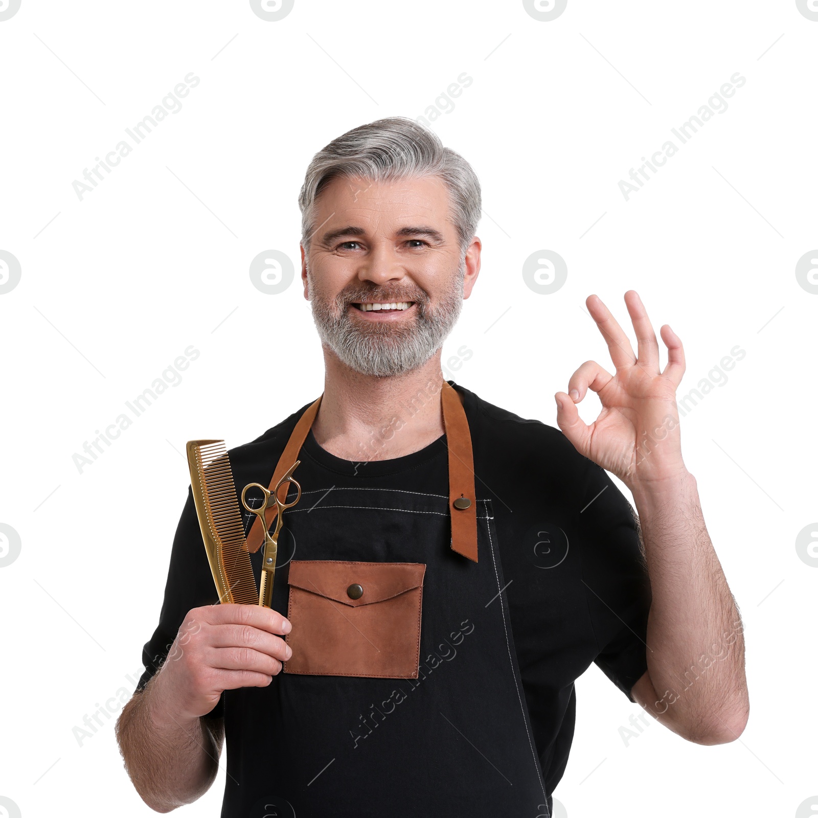 Photo of Smiling hairdresser with comb and scissors showing OK gesture on white background