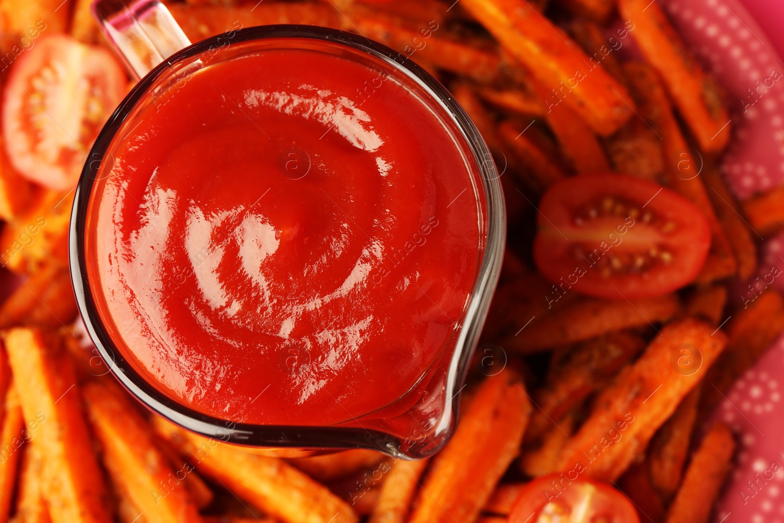 Photo of Tasty ketchup, tomatoes and fried carrots on plate, top view