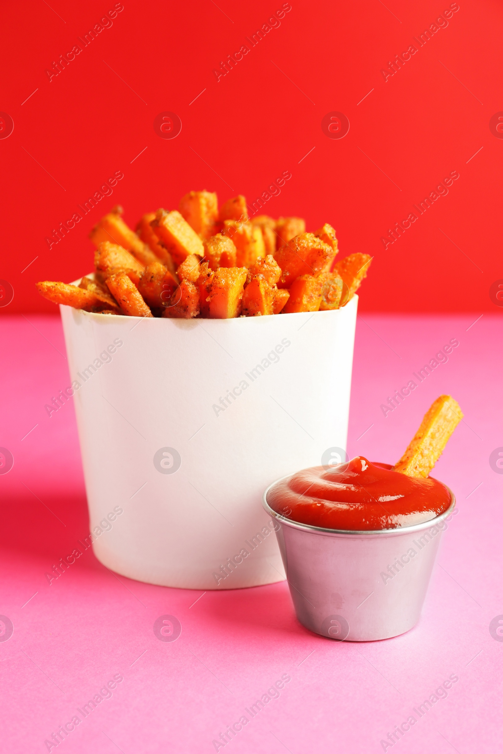 Photo of Tasty ketchup and fried carrots on color background