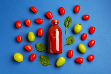 Photo of Tasty ketchup in bottle, tomatoes and basil on blue background, flat lay