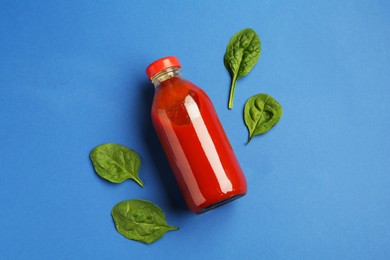 Photo of Tasty ketchup in bottle and basil on blue background, flat lay