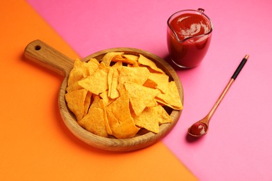 Photo of Tasty ketchup and nachos on pink background