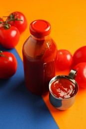 Photo of Tasty ketchup and tomatoes on color background, closeup