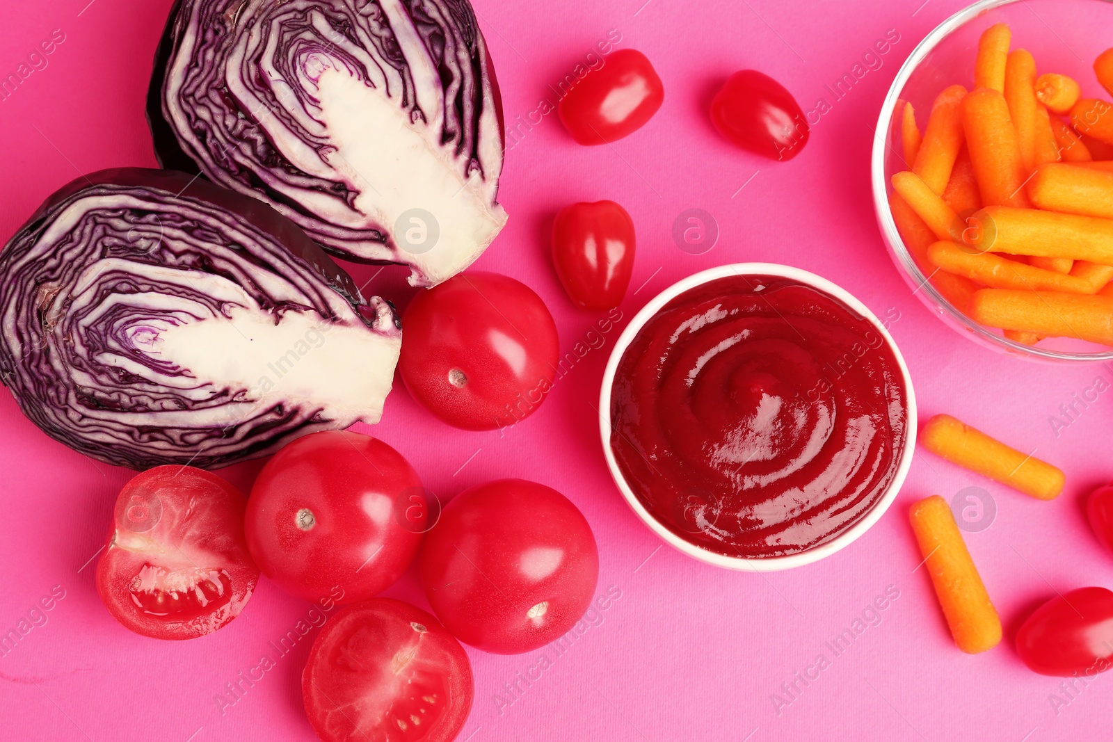 Photo of Tasty ketchup and vegetables on pink background, flat lay