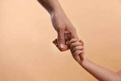 Photo of Father and child holding hands on beige background, closeup. Space for text