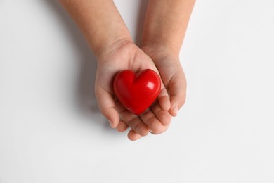 Photo of Child holding decorative red heart on white background, top view